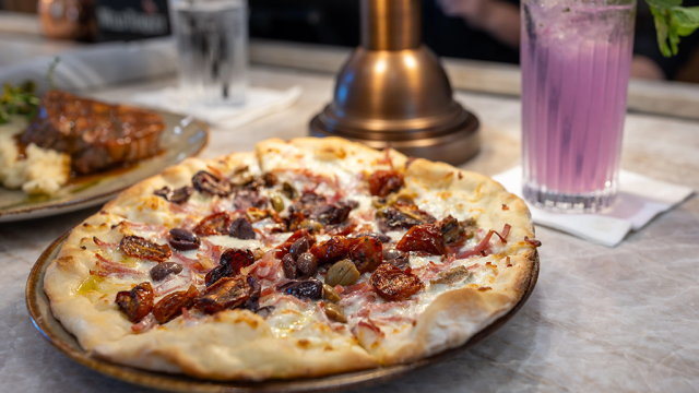 Pizza plate at Brickwood with cocktail and salmon dish in background